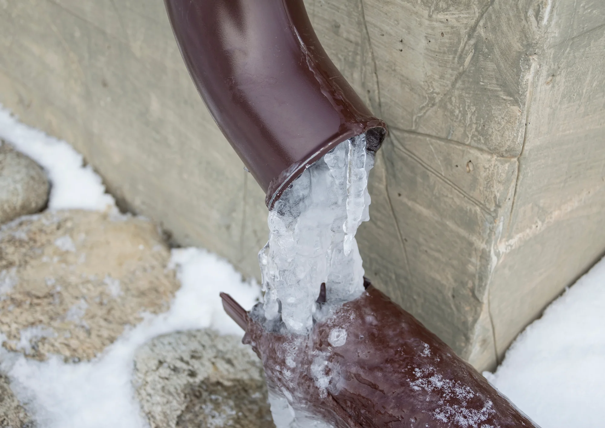 Close-up of icy pipe and outdoor plumbing showing the importance of winterizing exterior pipes before freezing temperatures.