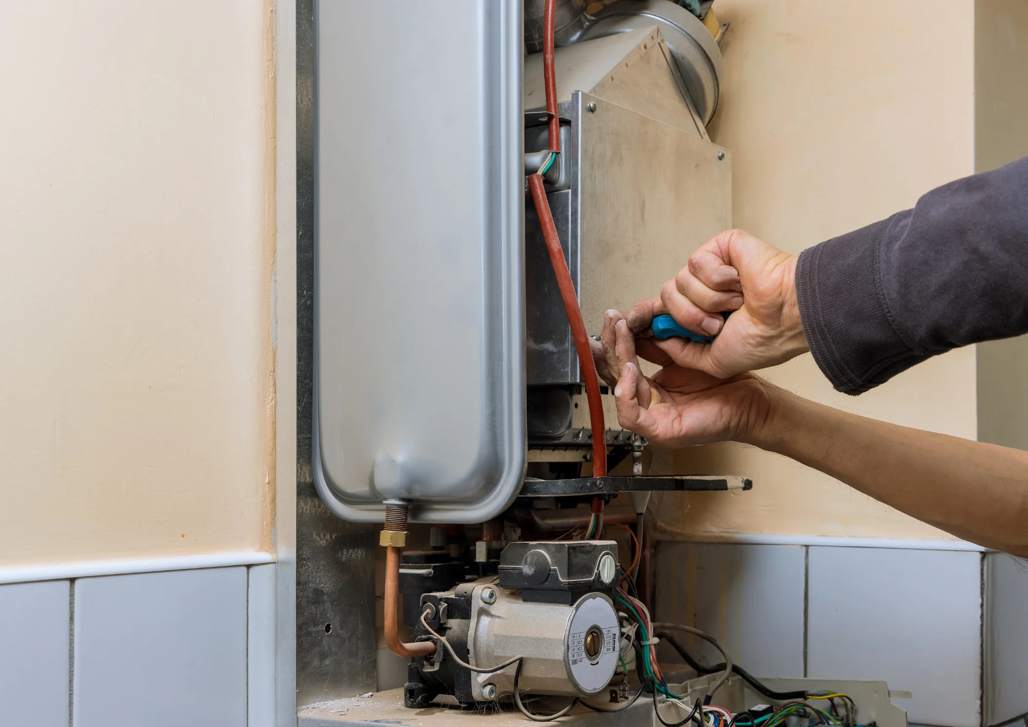 Repairman fixing a gas water heater in Rockwall, TX, demonstrating maintenance to extend lifespan